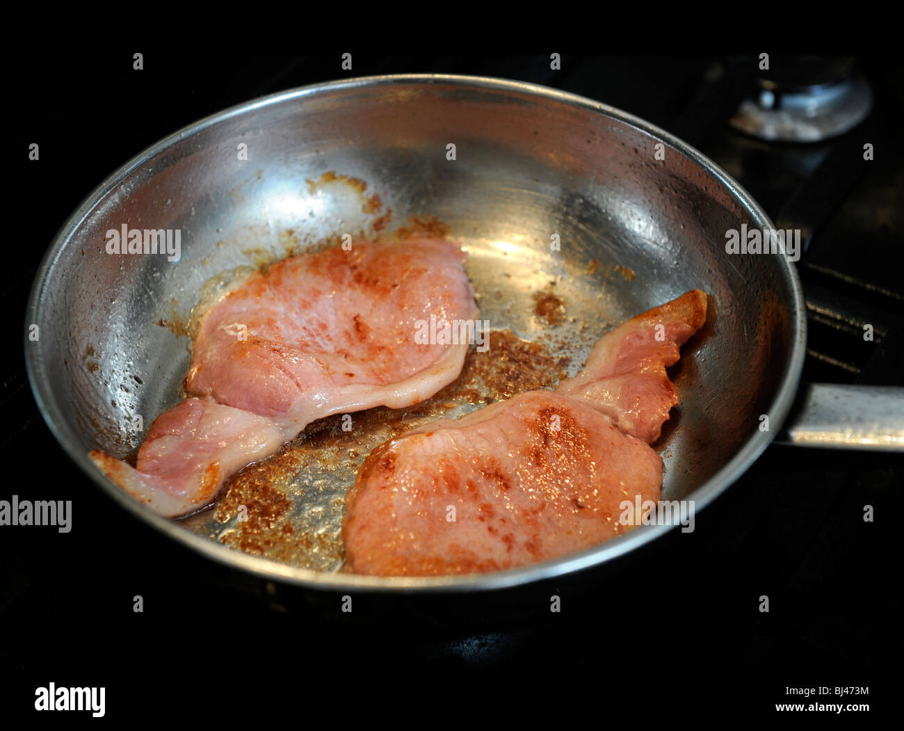 Zwei Speckscheiben Speck in einer Pfanne braten Stockfoto