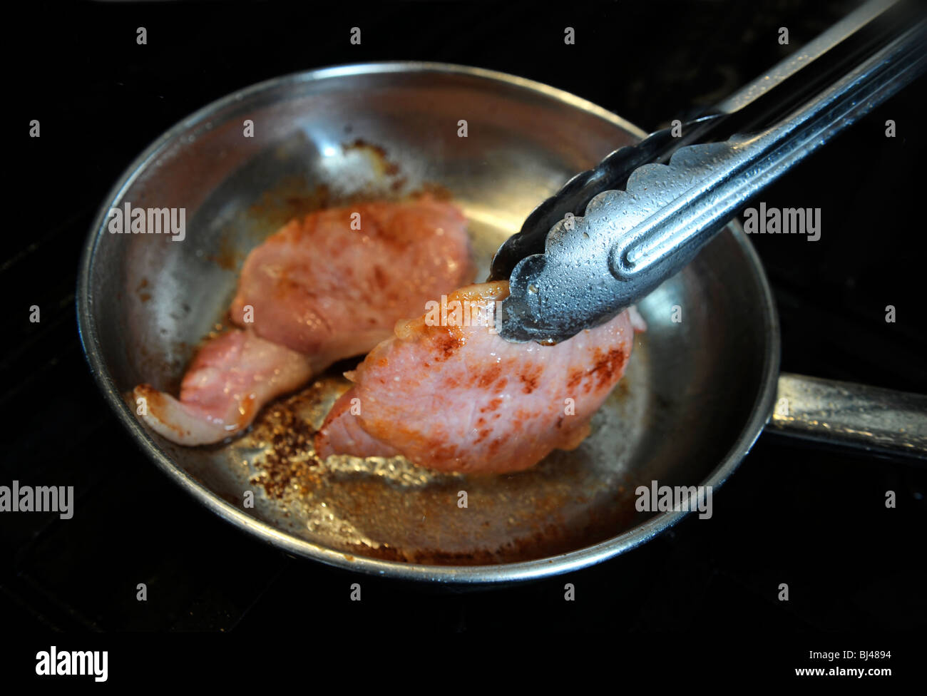 Zwei Speckscheiben Speck in einer Pfanne braten Stockfoto