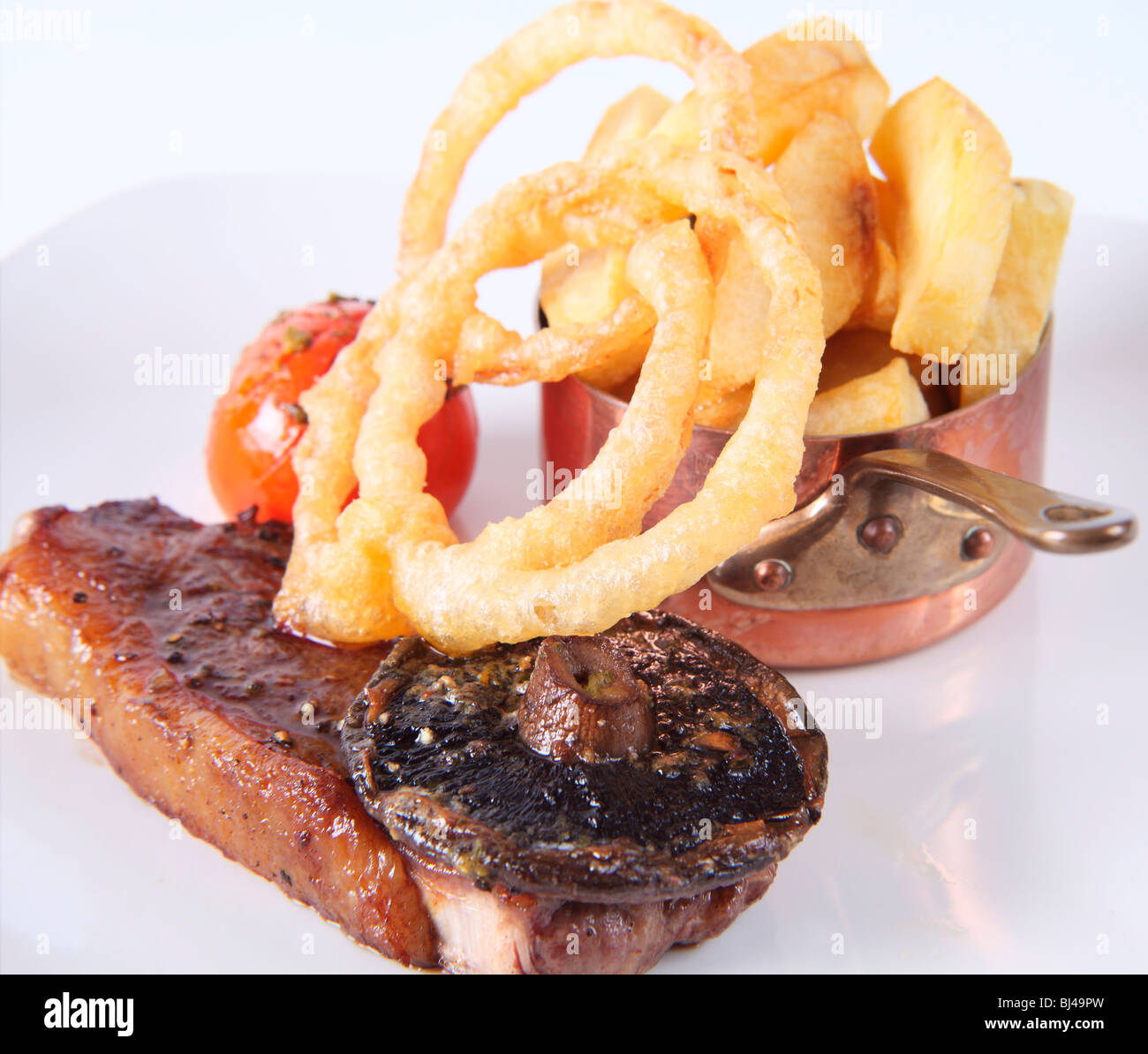 Gebratenes Entrecôte mit Pommes Frites und Tempura Teig Zwiebelringe Stockfoto