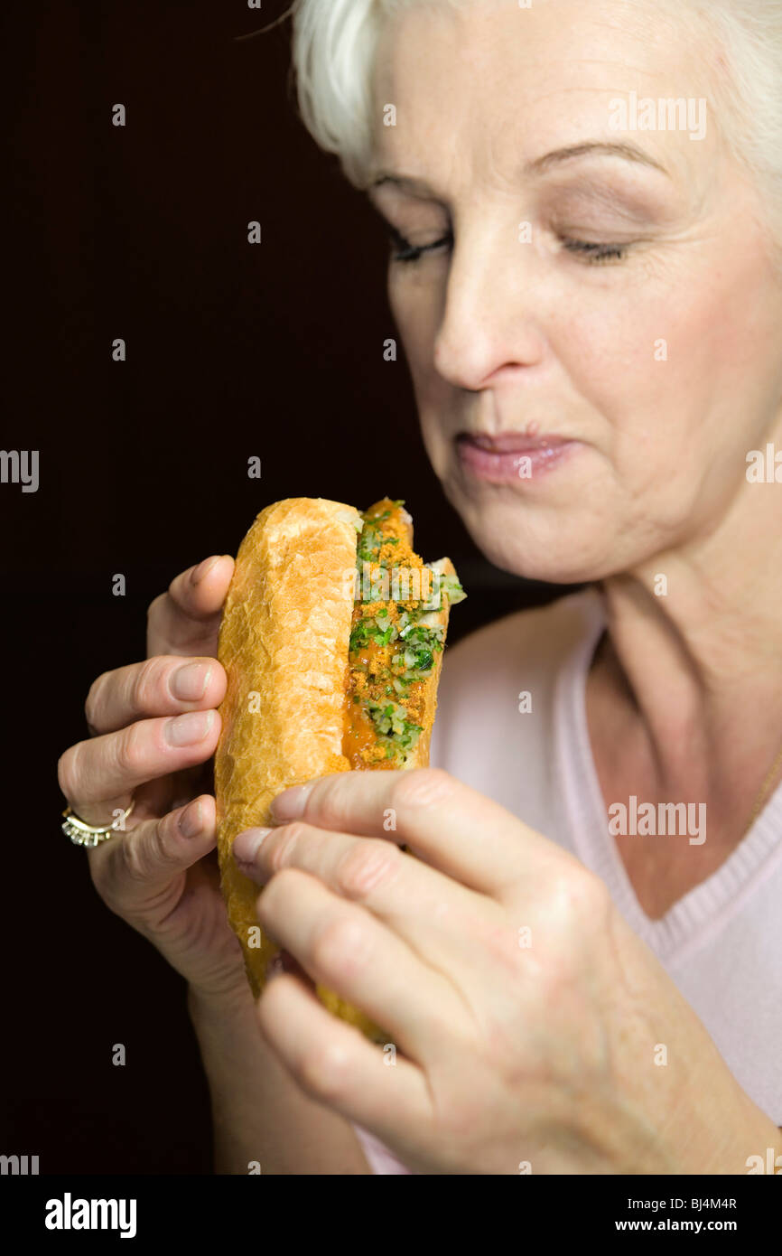 Eine Frau, die Verkostung einer Wurst in einem baguette Stockfoto