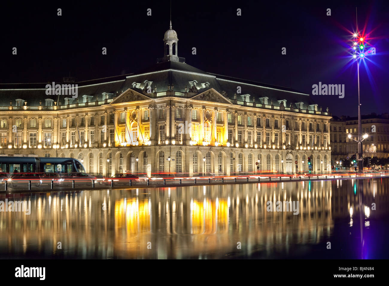 Bordeaux legen De La Bourse alte Börse Denkmal mit Pkw-Verkehr, Straßenbahn und Reflexion auf Wasser-Spiegel. Stockfoto