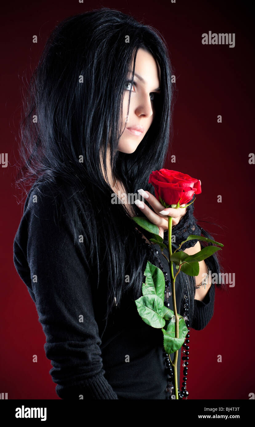 Goth-Mädchen mit roten Rose. Auf rotem Grund. Stockfoto