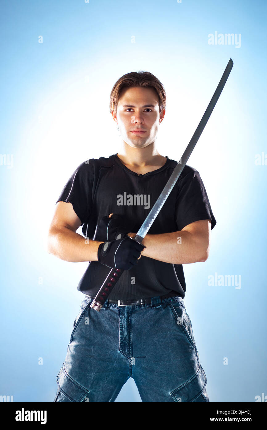 Starker Mann mit Samurai-Schwert. Auf weichen blauen Hintergrund. Stockfoto