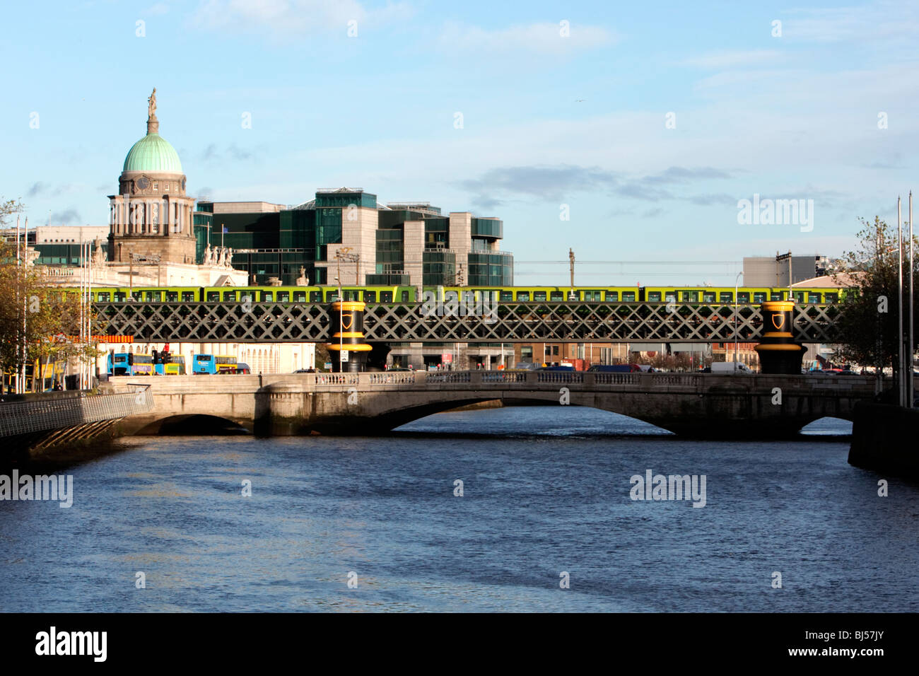 Der DART-Zug fährt über eine Brücke über den Fluss Liffey mit der Irish Financial Services Zentrum & Customs House im Hintergrund Stockfoto