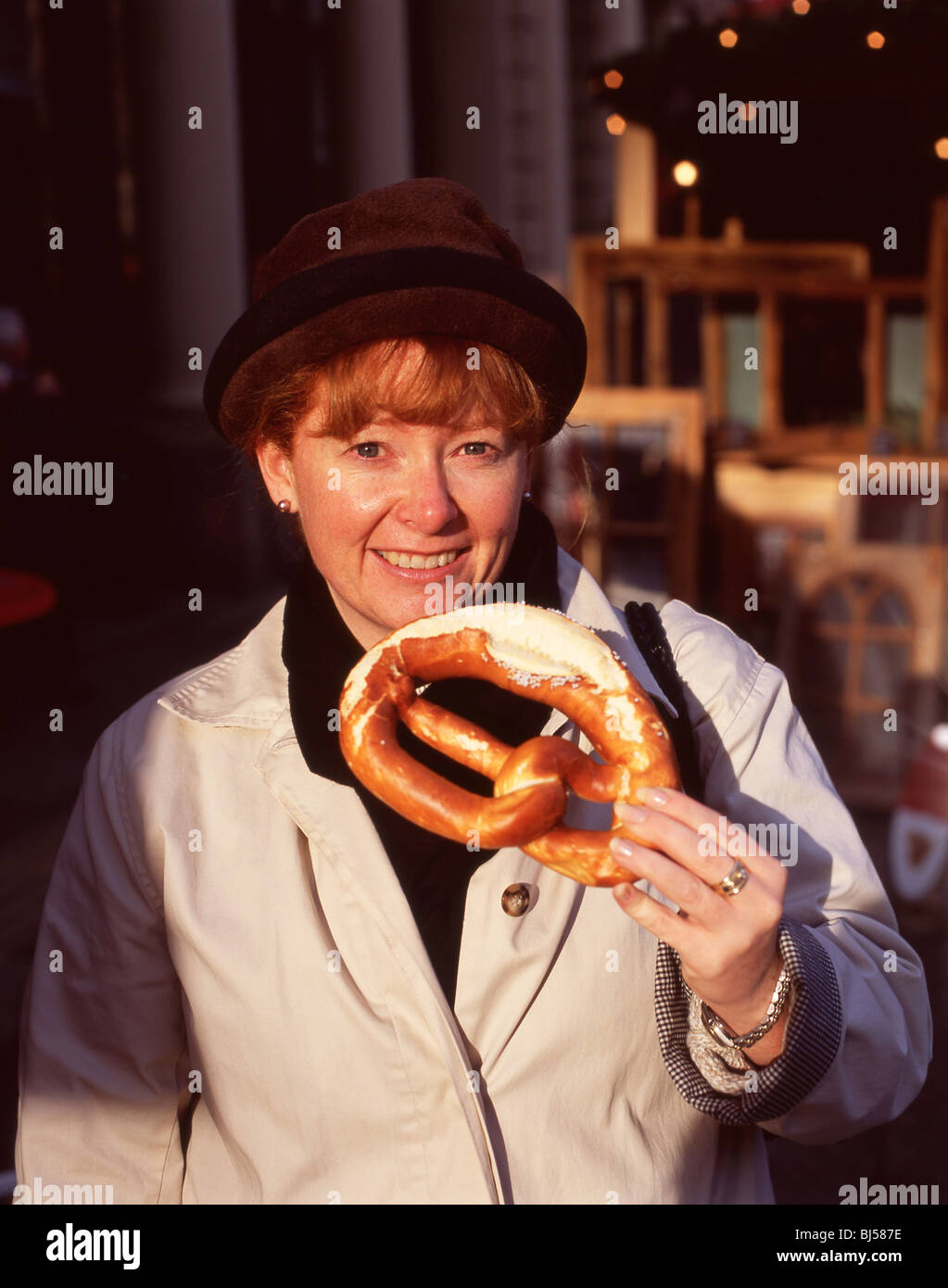 Junge Frau Essen Brezel, Alter Markt Weihnachtsmarkt, Köln (Köln), Nordrhein-Westfalen, Deutschland Stockfoto