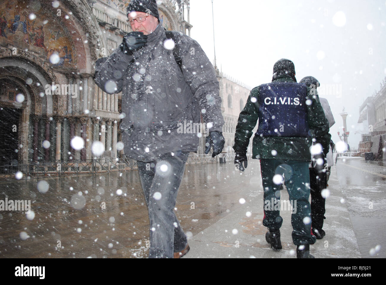 Männer zu Fuß entlang einem Gehweg während eines Schneesturms in einer überfluteten Markusplatz entfernt, Venedig, Italien Stockfoto