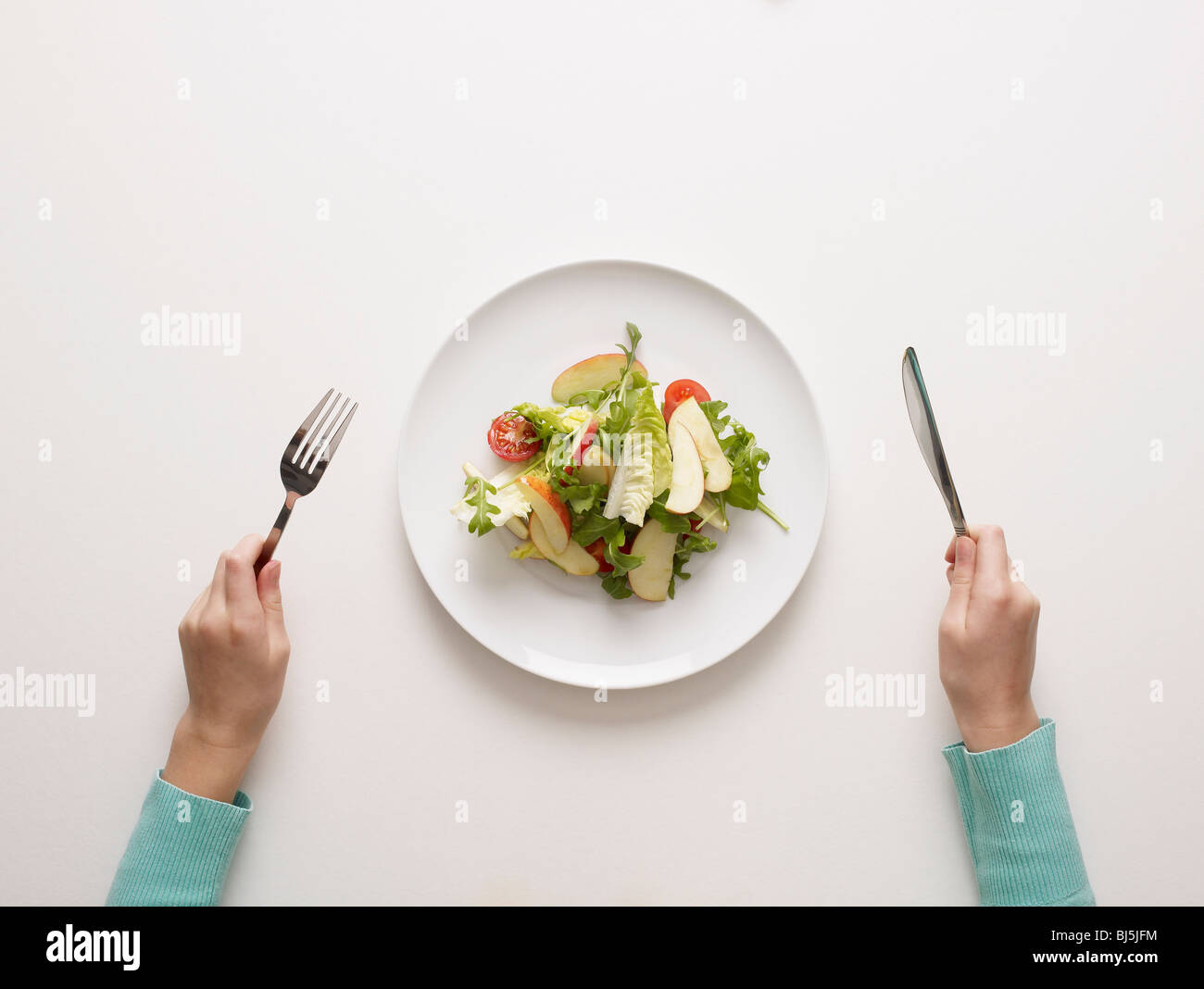 Hände durch einen Teller Salat Stockfoto