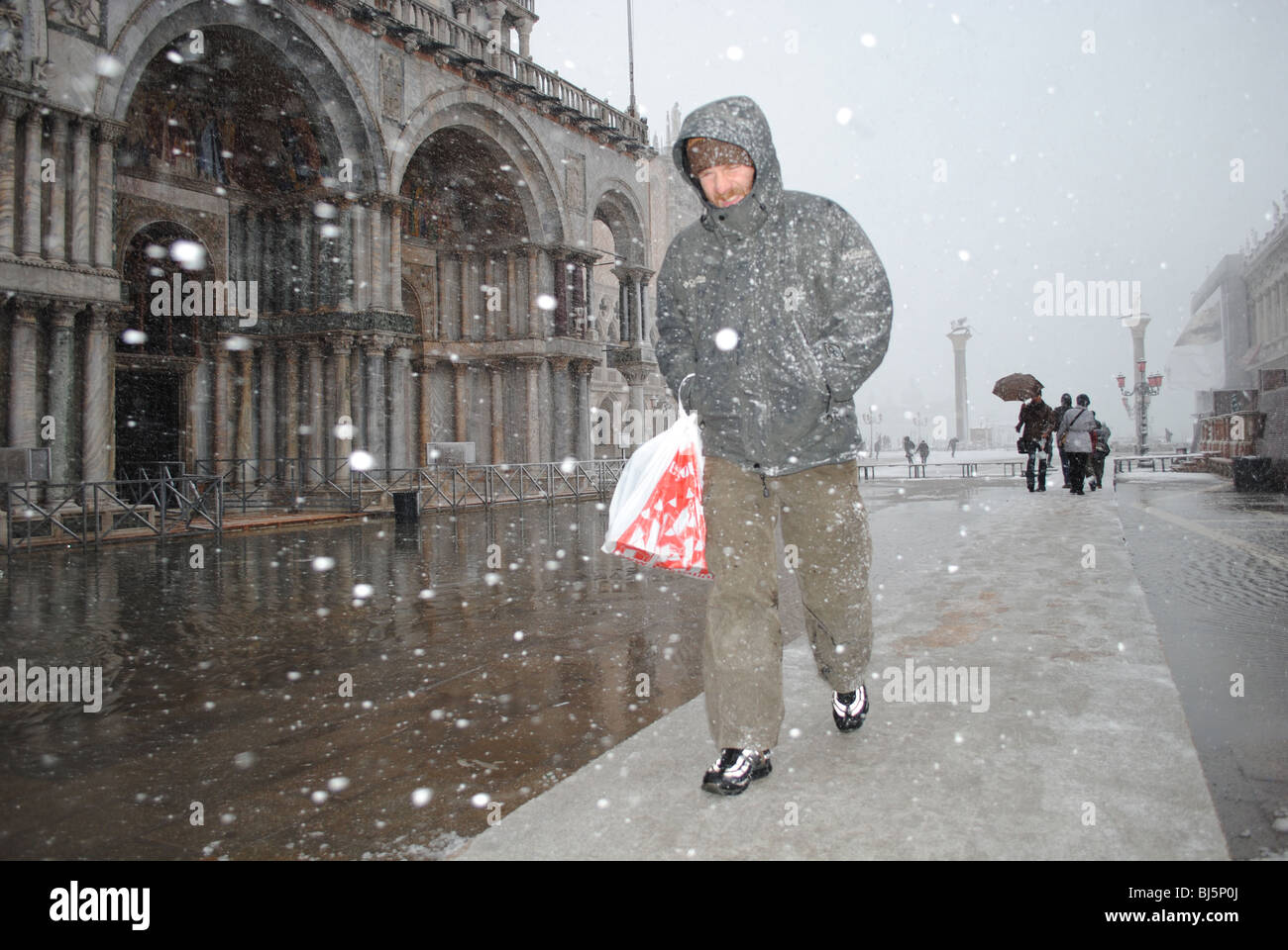 Mann auf Gehweg in einem Schneesturm in einer überfluteten Markusplatz entfernt, Venedig, Italien Stockfoto
