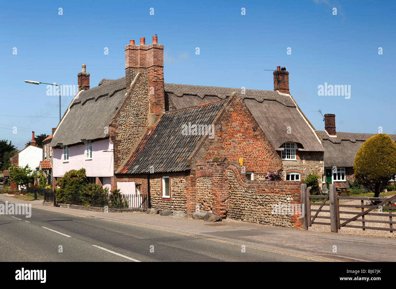 Bacton, Broomholm Dorf, Norfolk, England, UK attraktive Pastell rosa lackiert Reetdachhaus Stockfoto