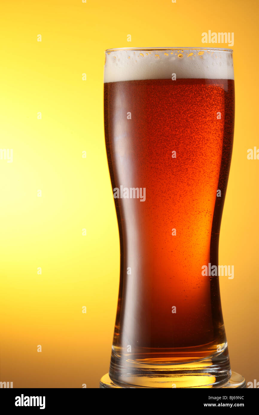 Glas dunkel Bier auf gelbem Hintergrund Stockfoto