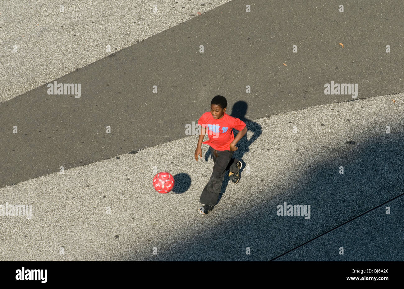 Ein Junge spielt Fußball auf der Straße, Basel, Schweiz Stockfoto