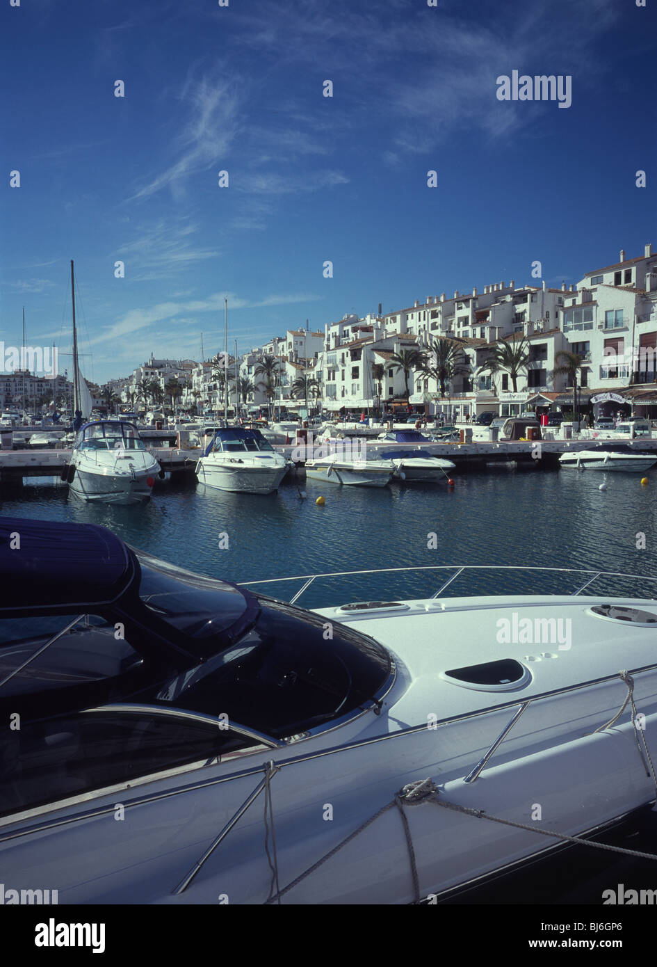 Luxus-Kabine-Kreuzer in Puerto Banus Marina mit Wohnungen und Kai Geschäfte jenseits - Marbella, Spanien Stockfoto