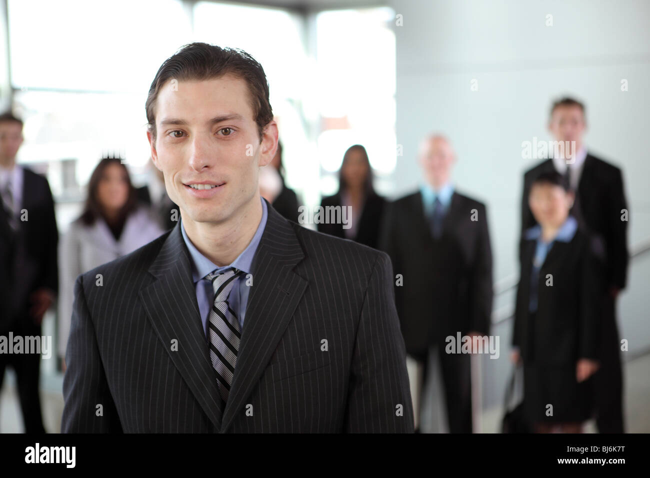 Porträt des jungen Geschäftsmann mit Menschen im Hintergrund Stockfoto
