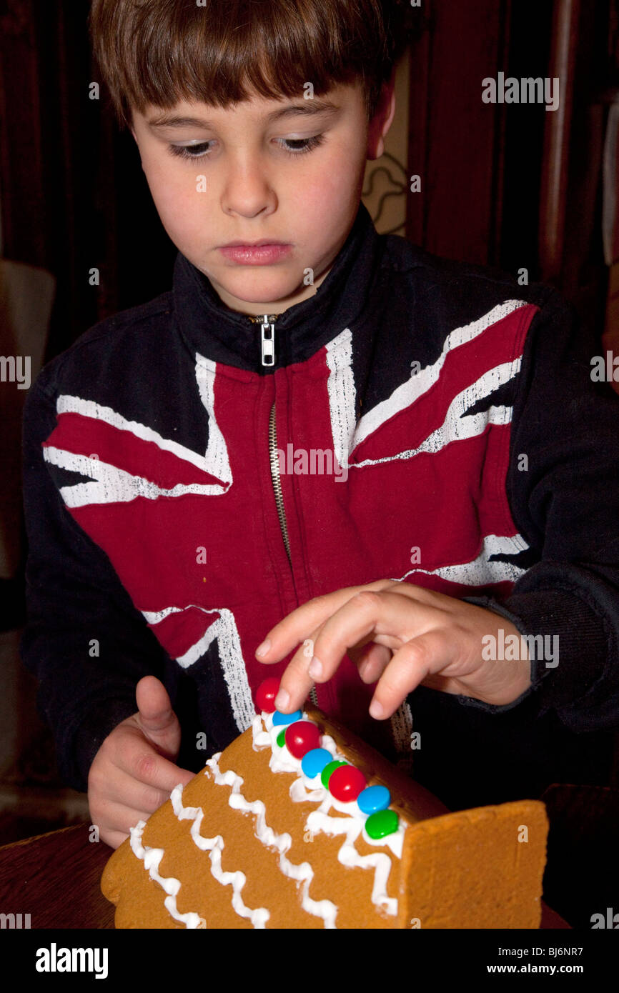 Jungen Alter 7 ein UK Union Jack Flag t-Shirt ein Weihnachtshaus Lebkuchen verzieren. St Paul Minnesota USA Stockfoto