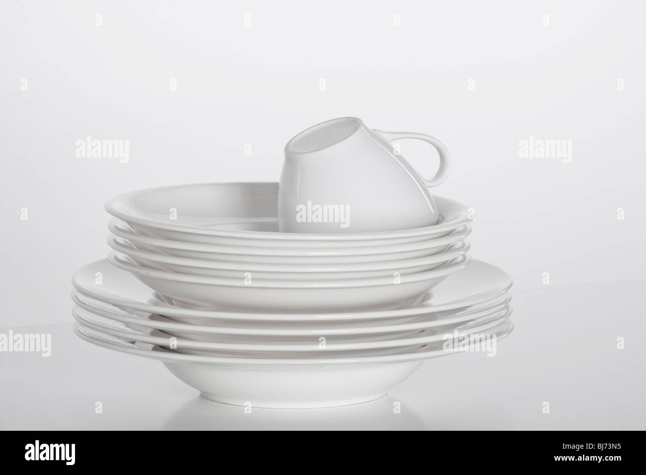 Studioaufnahme von einem Stapel von weißen Teller und weißen Tasse isoliert auf weiss Stockfoto