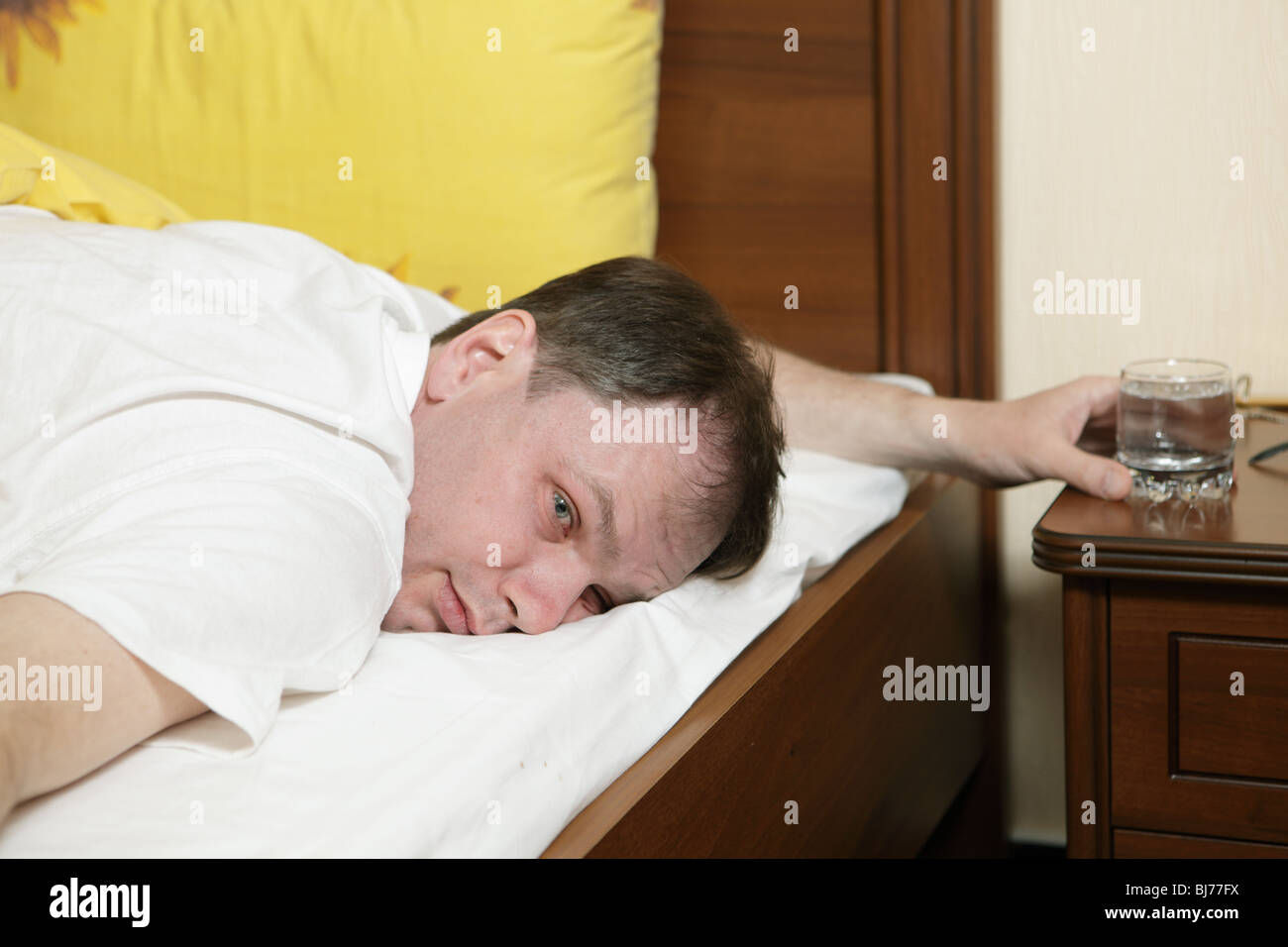 Betrunkener Mann im Bett mit einem Glas Stockfoto