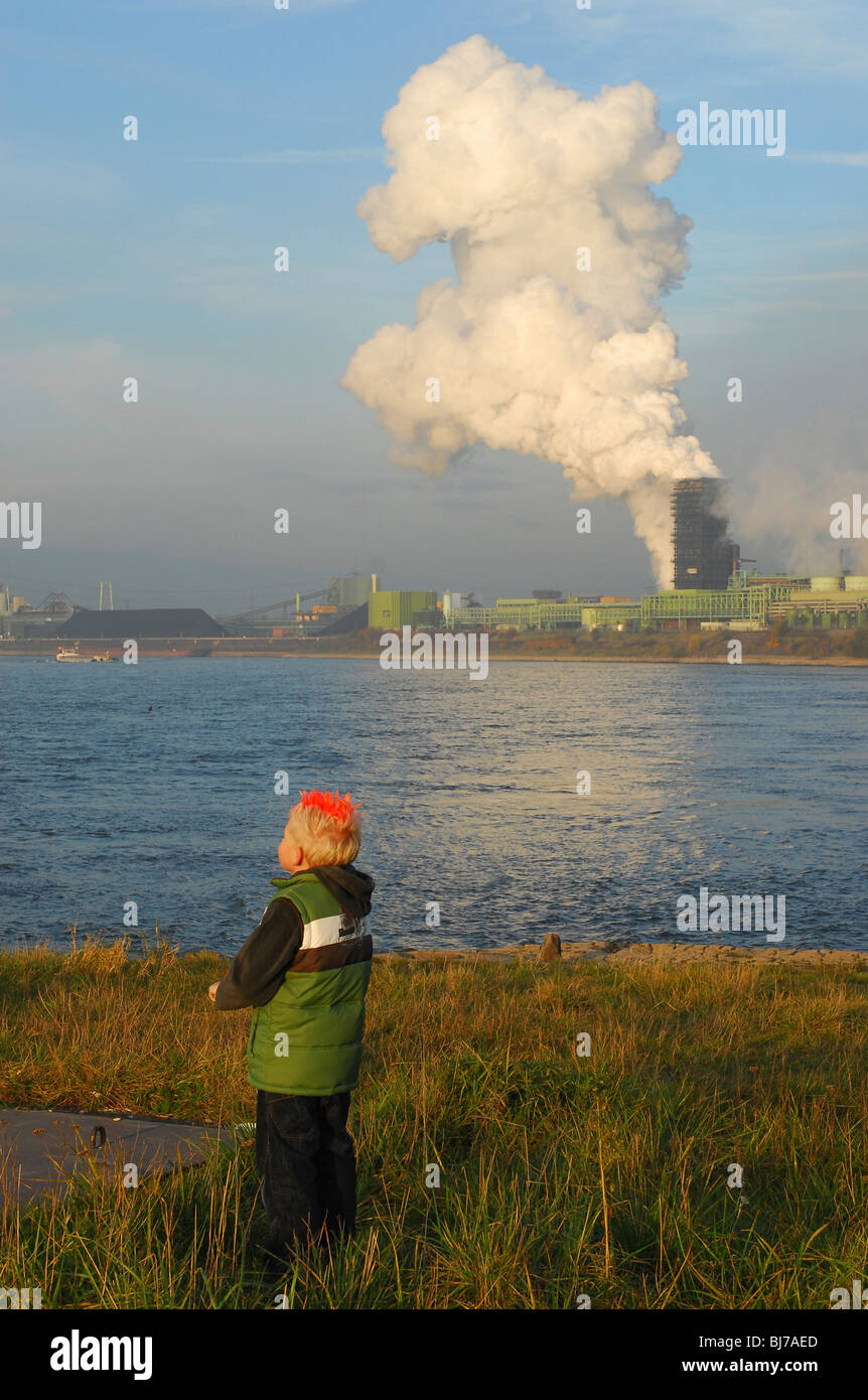 Junge stand an einem Fluss mit der ThyssenKrupp Stahl AG Kokerei im Hintergrund, Duisburg, Deutschland Stockfoto