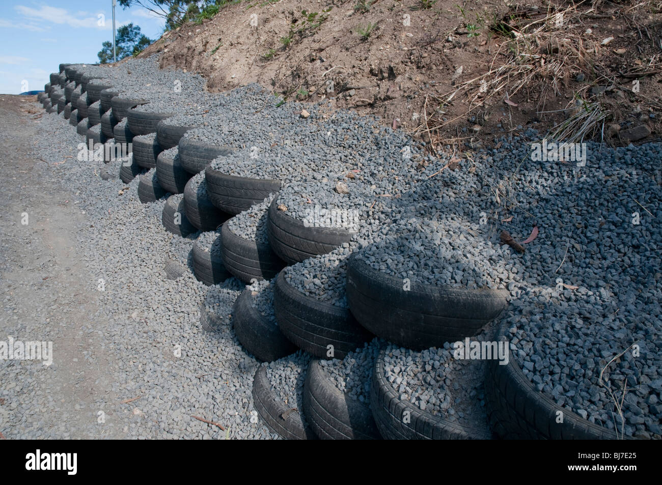 Recycelte Reifen und Kies als Stützmauer auf einer Auffahrt Stockfoto