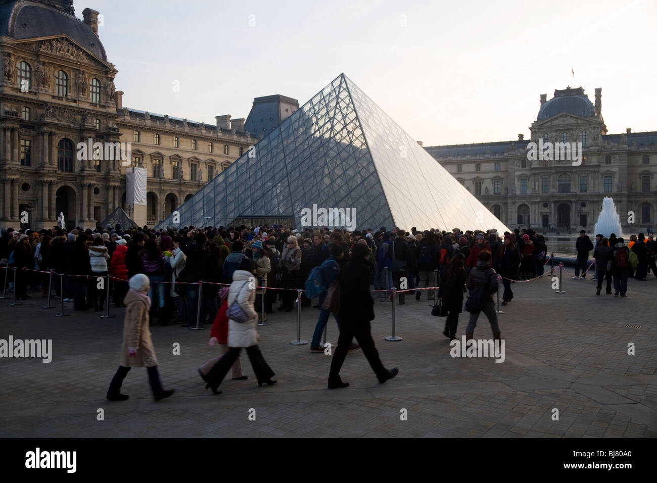 Menschen in die Warteschlange im Morgengrauen zum kostenlosen Eintritt in das Louvre Museum / Musée / Palais du Louvre, neben der Glaspyramide. Paris, Frankreich. Stockfoto
