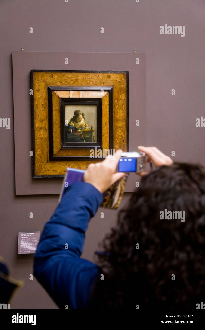 Frau-Tourist mit dem digitalen fotografieren die Spitzenklöpplerin Gemälde von Vermeer, Jan. Das Louvre, Paris. Frankreich. Stockfoto