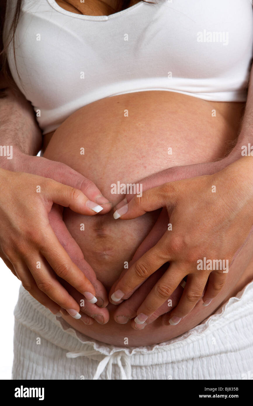 8 Monate schwanger 30 jährige Frau mit 37 Jahre alten männlichen Partner holding übergibt Babybauch Stockfoto
