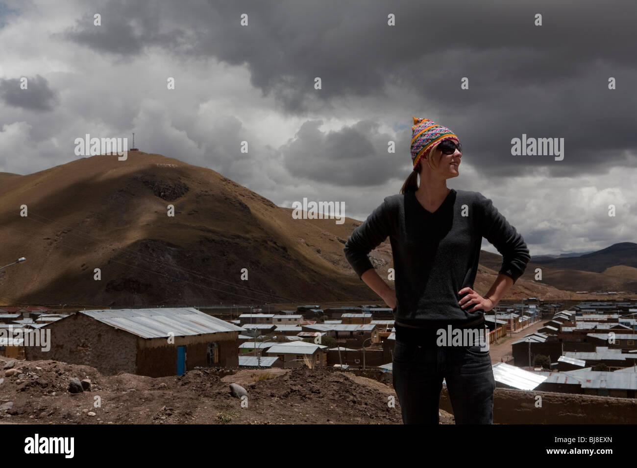 westliche Frau im traditionellen Hut und eine Sonnenbrille stehen vor der peruanischen Bergdorf Stockfoto