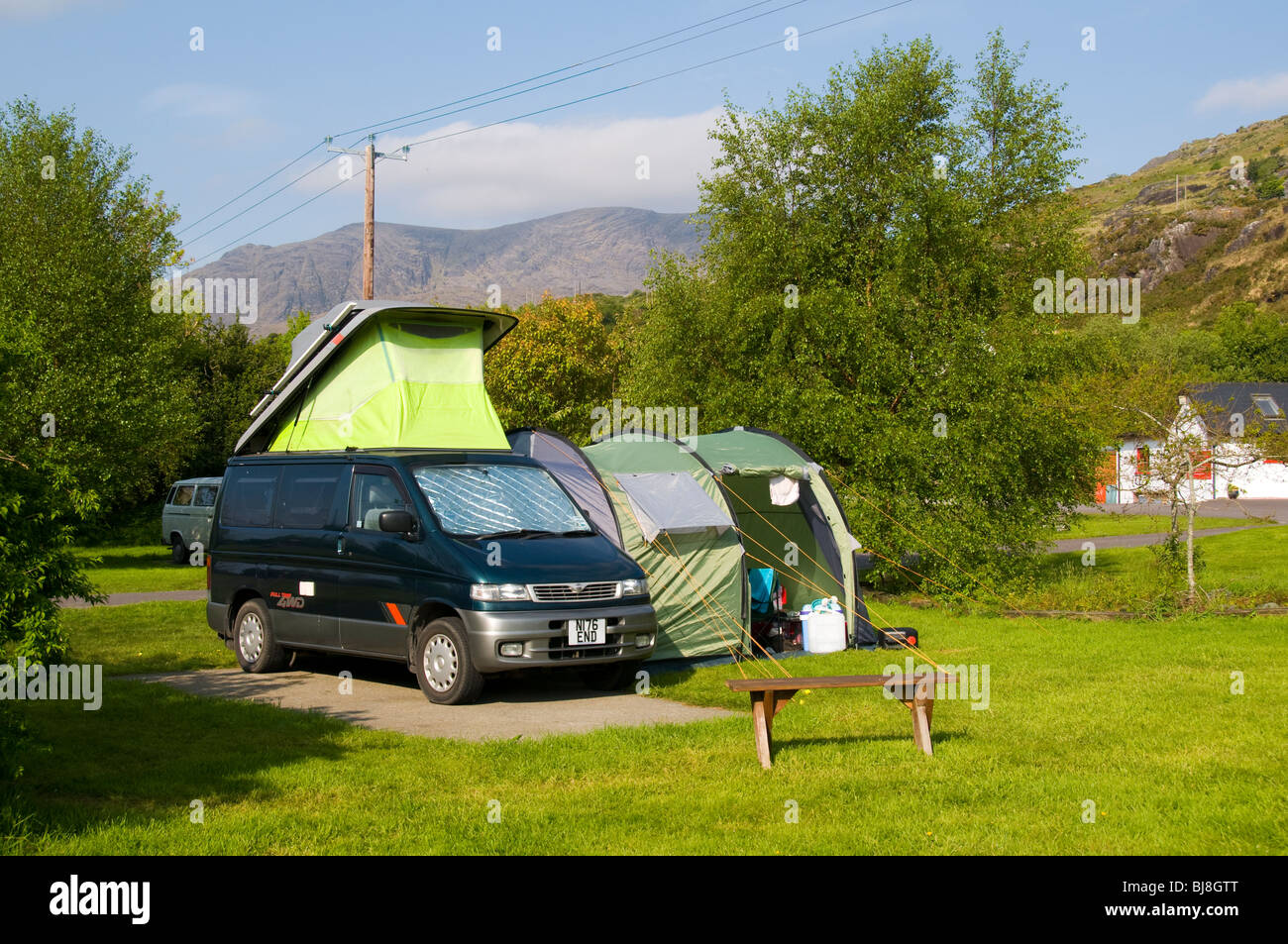 Ein kleines Wohnmobil mit Seite Vorzelt auf einem Campingplatz in Adrigole, Beara Halbinsel, County Cork, Irland.  Hungry Hill hinter. Stockfoto