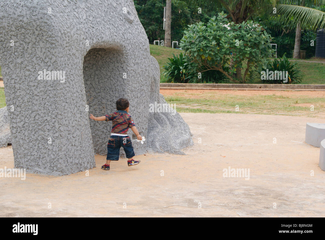 Kleines Kind Herumspielen Skulptur ein großen Stein in Veli Tourist Village in Trivandrum (Kerala, Indien) Stockfoto