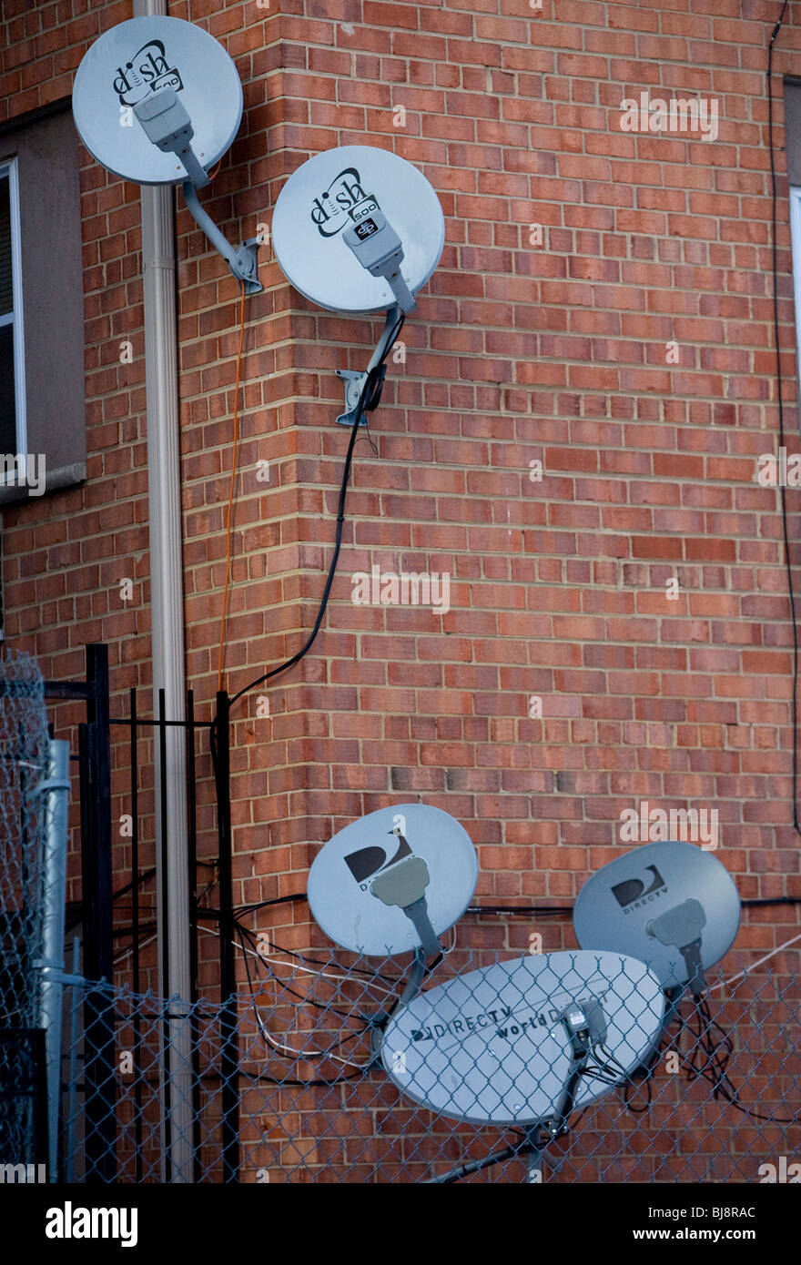 DirecTV und Teller-Netz Satellitenschüsseln auf einem Mehrfamilienhaus. Stockfoto