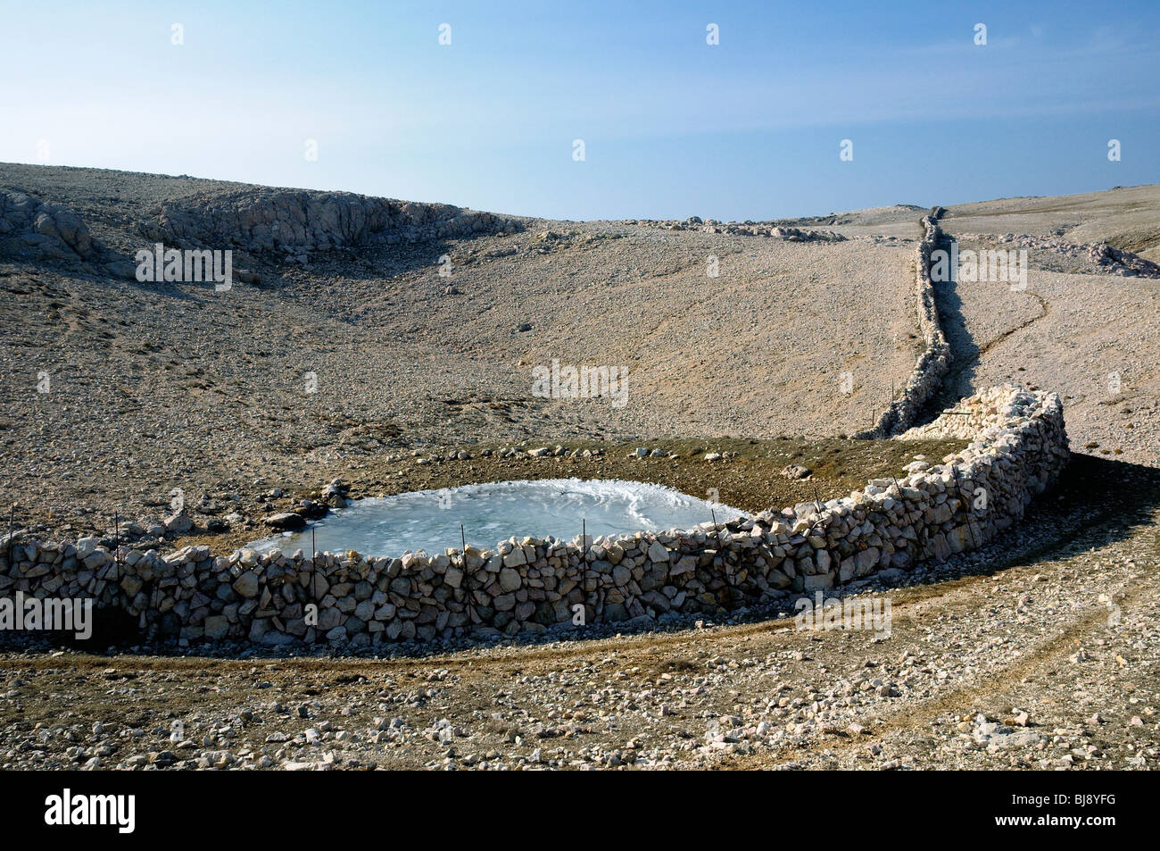 Ödland Karstlandschaft mit gefrorenen Wasserloch und Trockenmauer, Obzova Berg, Insel Krk, Kroatien Stockfoto