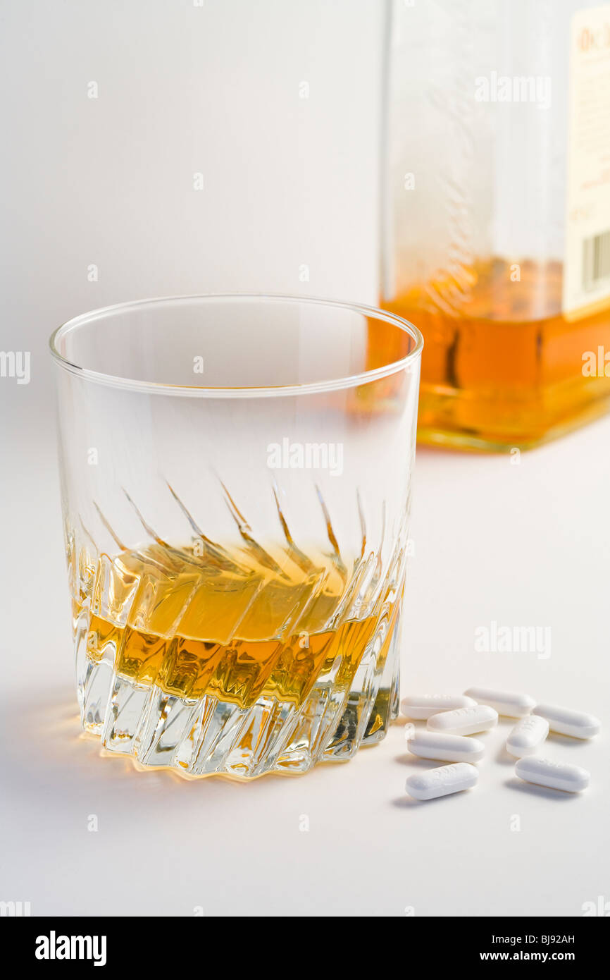 Eine Flasche und ein Glas Whiskey mit einige Pillen Stockfoto