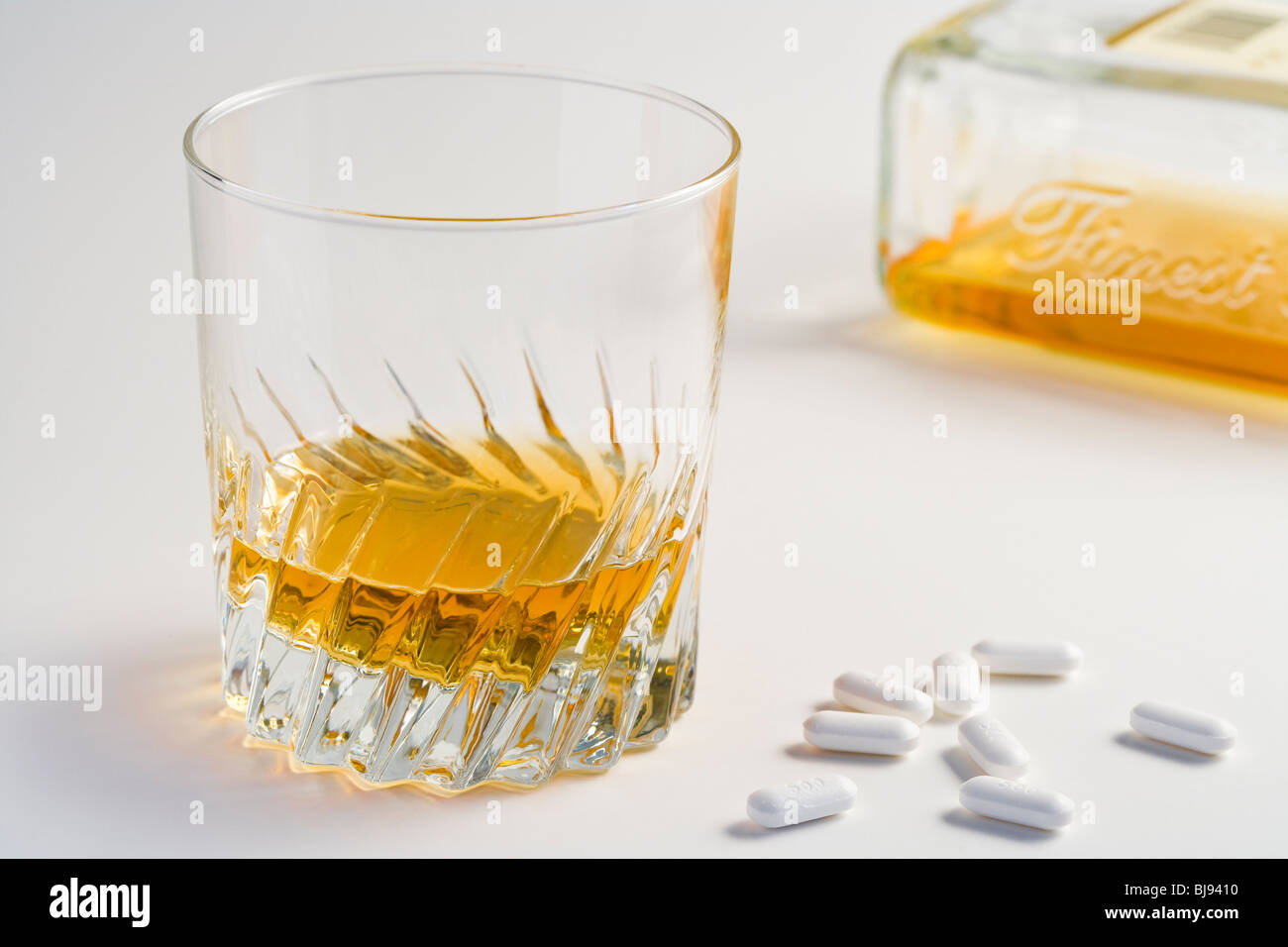Eine Flasche und ein Glas Whiskey mit einige Pillen Stockfoto