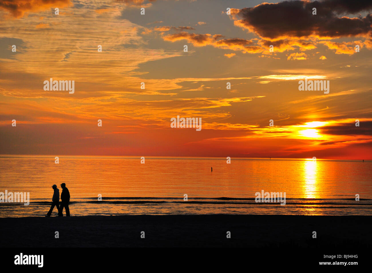 Ein paar Spaziergänge am Strand bei Sonnenuntergang Stockfoto
