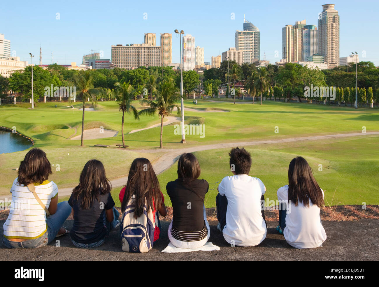 Junge philippinische sitzend auf Intramuros Wand mit Blick auf Golf Club, Manila; Intramuros; Manila; Philippinen Stockfoto