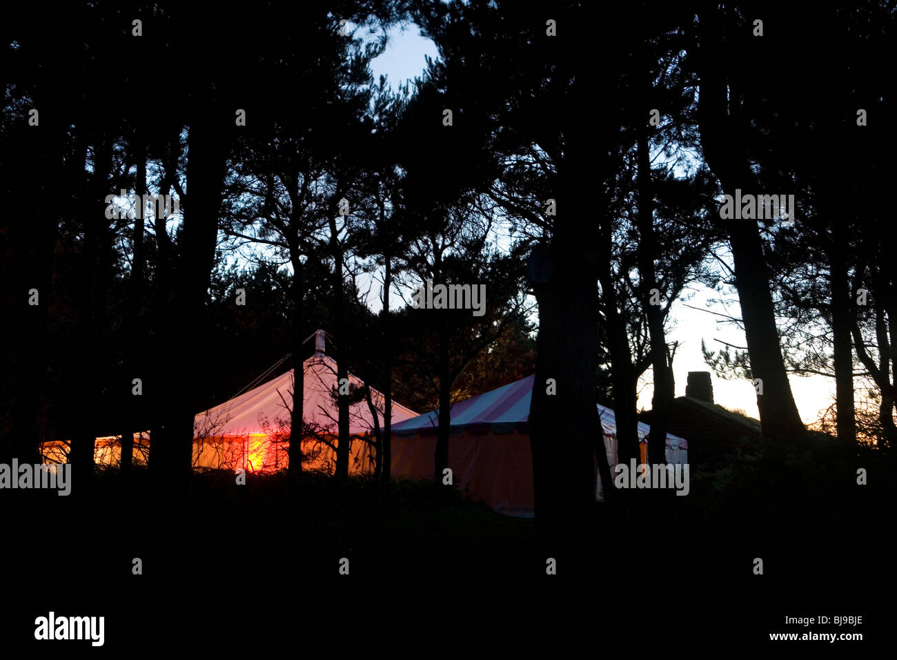 Party-Zelten im Wald bei Sonnenuntergang leuchtet von innen Stockfoto