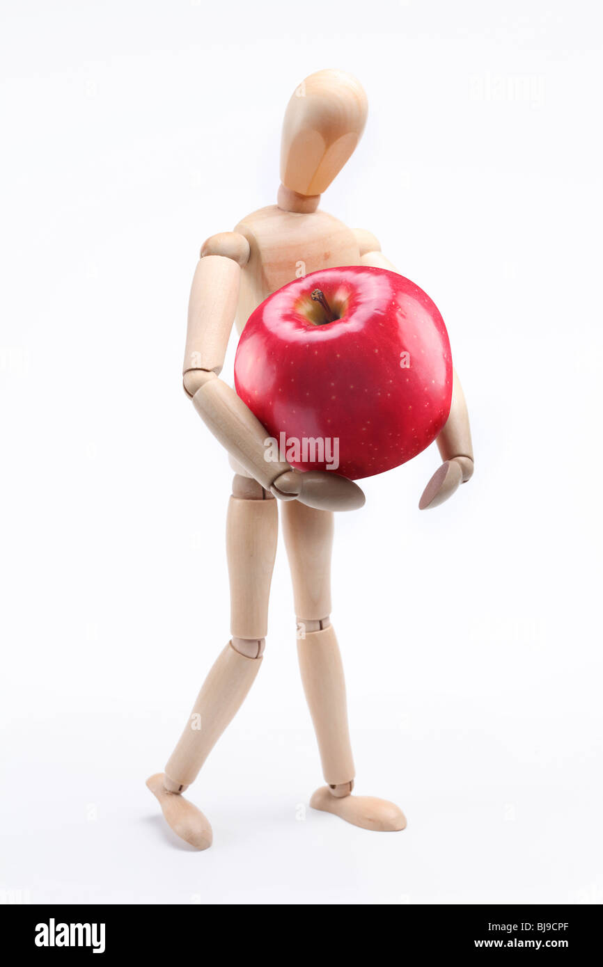 Hölzerne Mann hält einen großen roten Apfel. Isoliert auf weiß Stockfoto