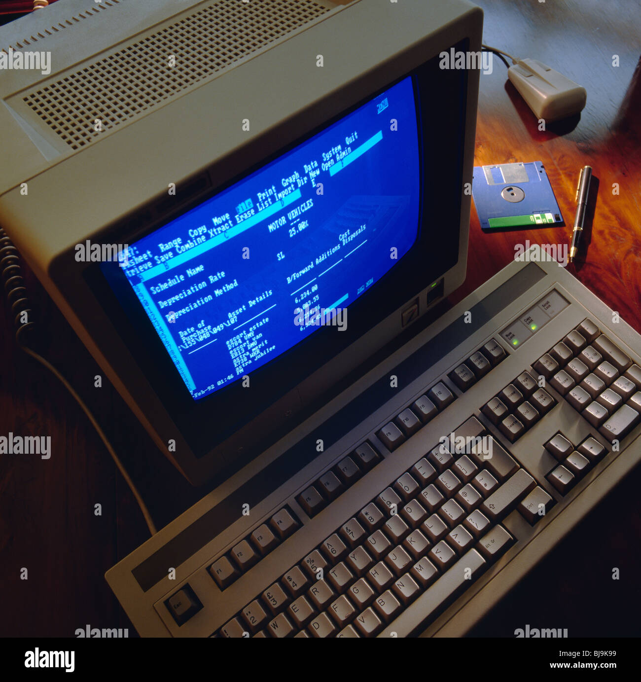1990 Computer alten Büroschreibtisch Buchhaltung Finanztechnologie Terminal Bildschirm & Tastatur mit Diskette & Maus auf 90s Stil Holz Schreibtisch Stockfoto