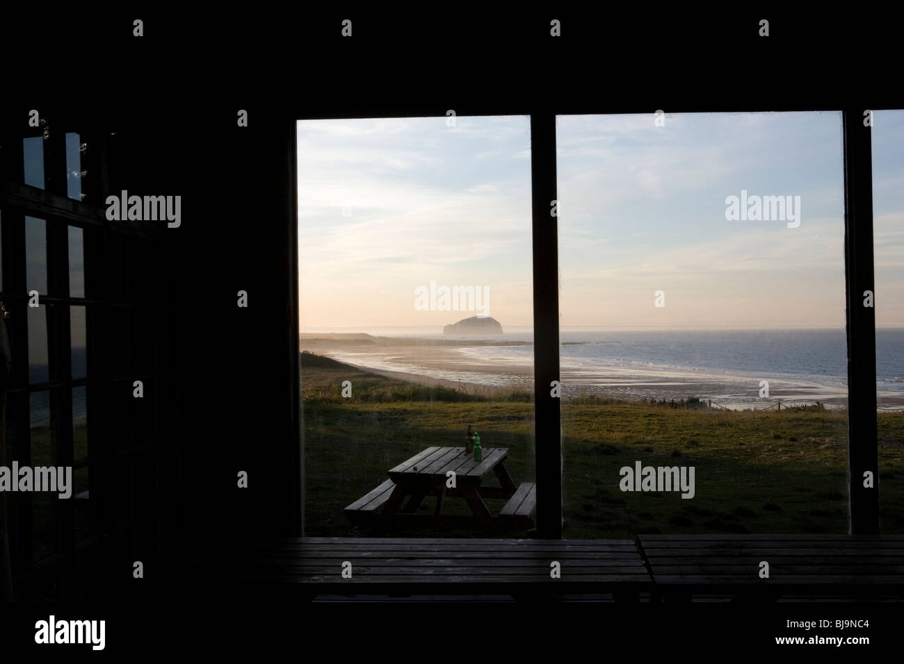 Blick auf schottischen Strand und Küste durch die großen Fenster des Holzhaus Stockfoto