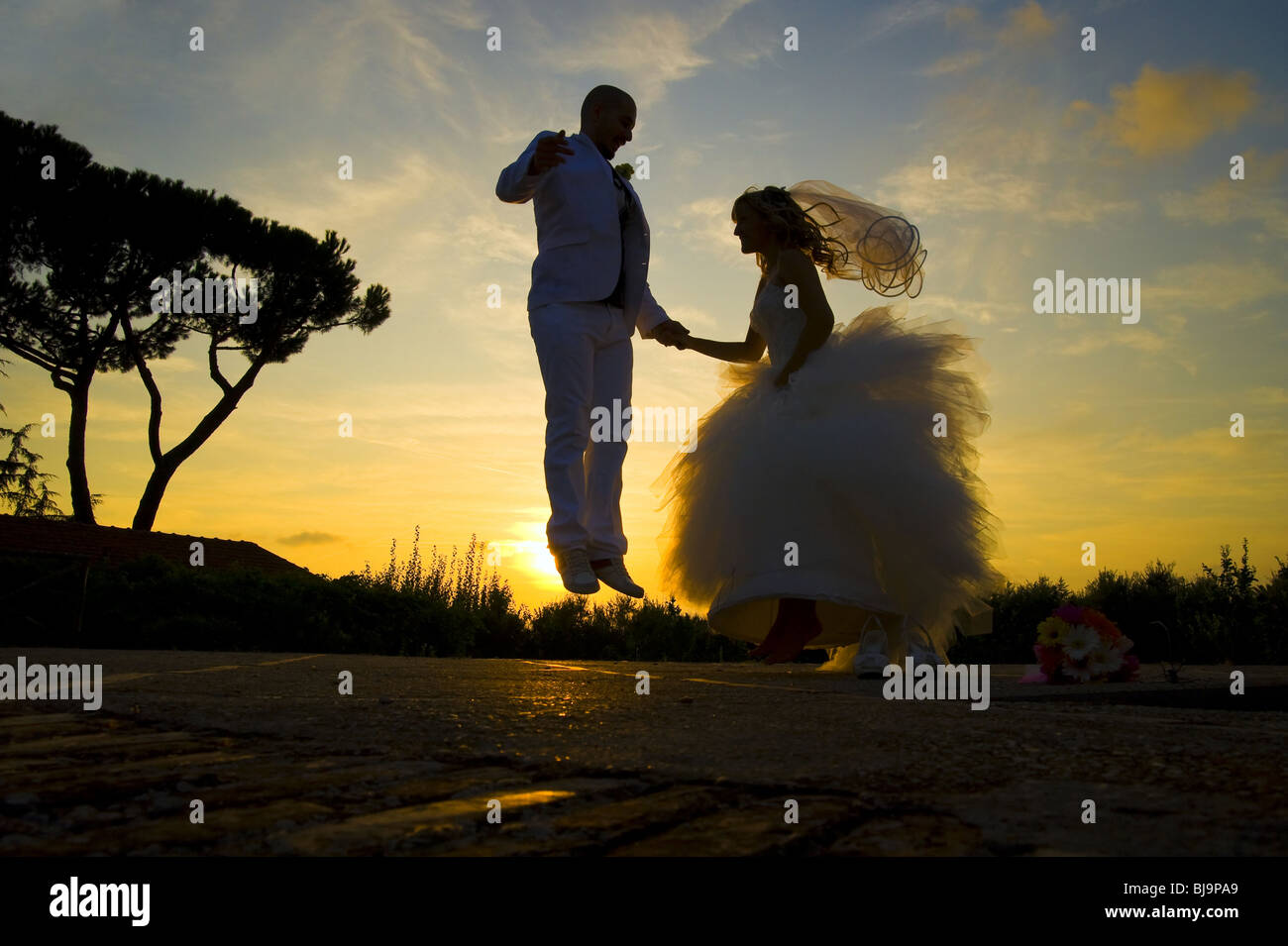 Braut und Bräutigam springen vor Freude bei Sonnenuntergang Stockfoto