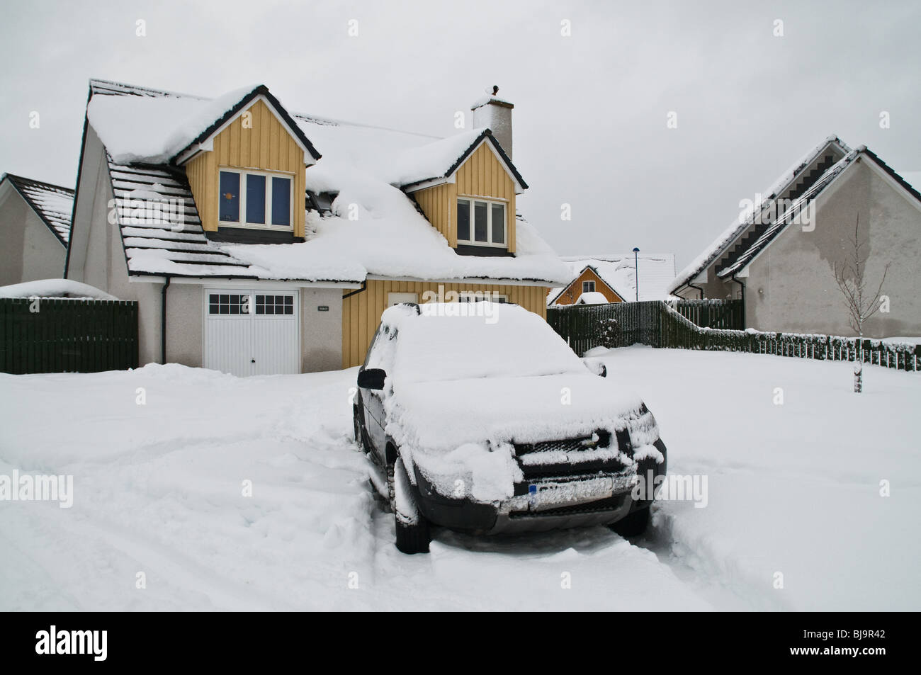 dh AVIEMORE INVERNESSSHIRE Schneebedecktes Auto im Gartenhaus Fahrt verschneiten Winter schottland Zuhause Exterior scottish Highlands Winterzeit eiskalt großbritannien Stockfoto