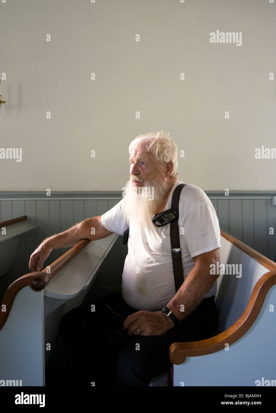 Alter Mann mit einem langen weißen Bart sitzt in einer alten holländischen Kirche Pew hören Stockfoto