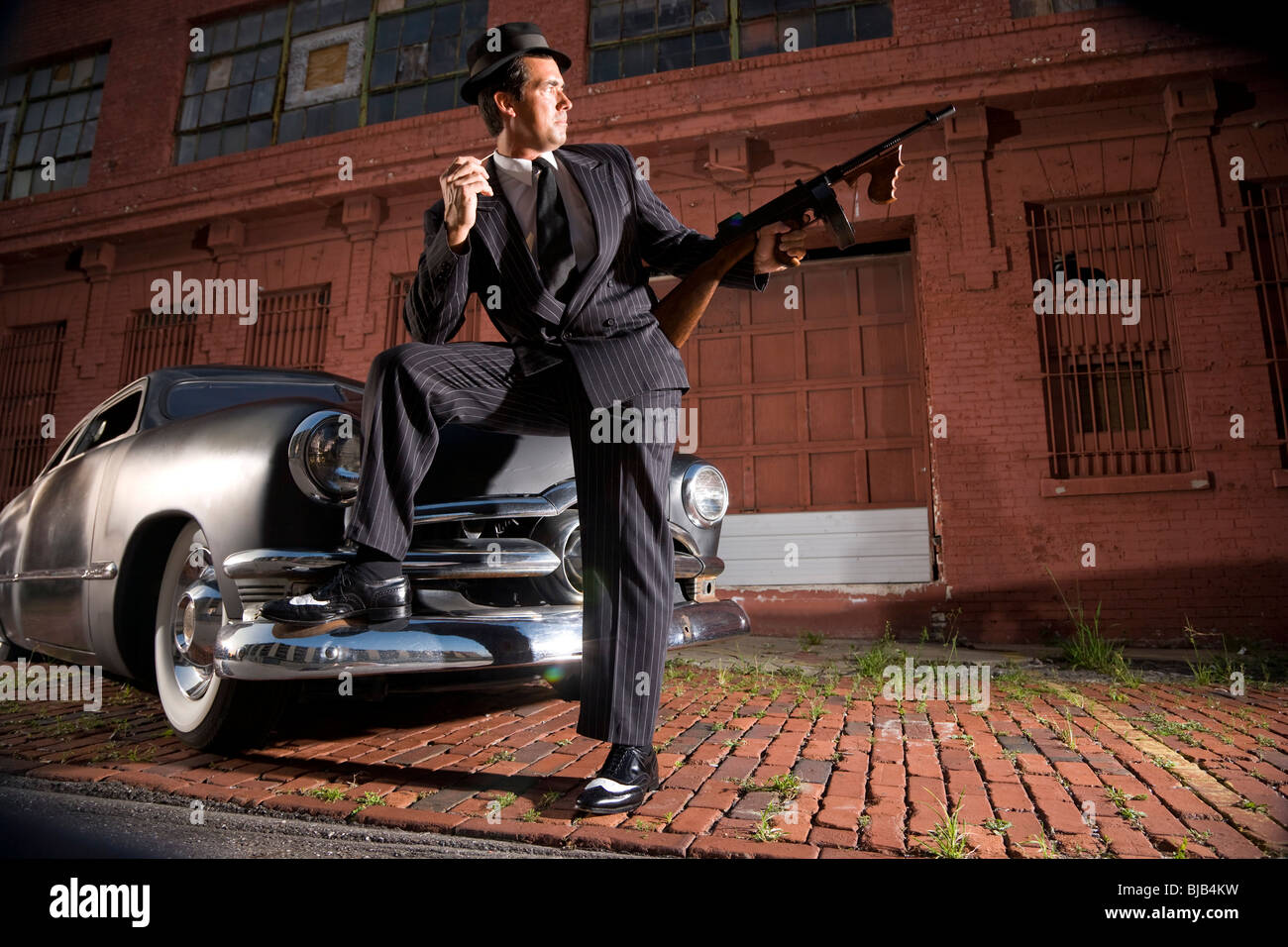 Gangster hält Tommy Gun stützte sich auf Oldtimer Stockfoto