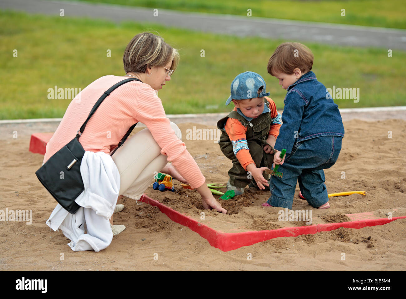 Mutter mit Kindern im Sandkasten spielen Stockfoto
