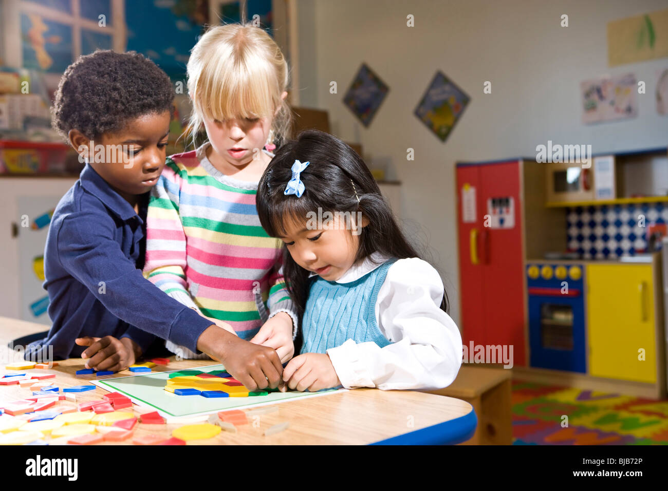 Drei Kinder im Vorschulalter arbeiten gemeinsam an bunten Shape puzzle Stockfoto