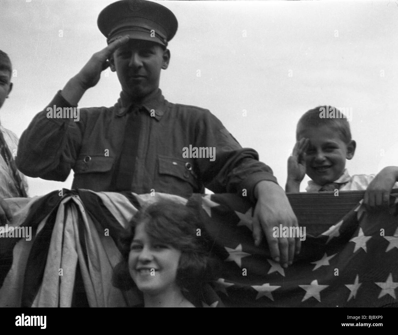 Ein Mann und ein Junge Gruß neben Sternen und Streifen während der Parade der 1940er Jahre Americana WWII Veteranen Tierärzte patriotische Amerikaner Patriotismus Stockfoto