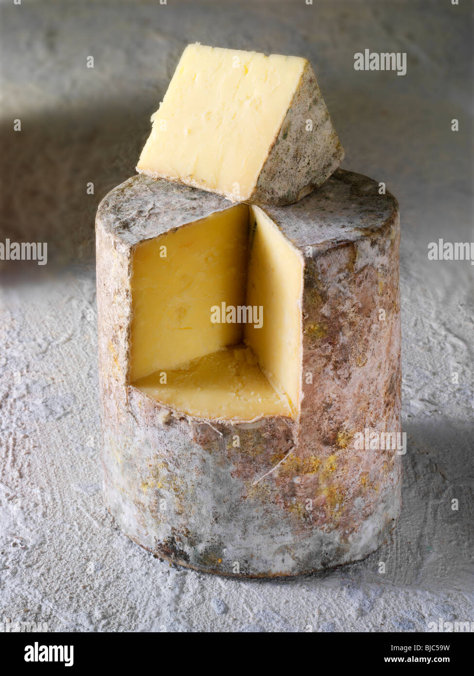 Traditionelle britische Bauernhaus Cheddar Käse Tuch gebunden truckle mit einem Keil ausgeschnitten Stockfoto