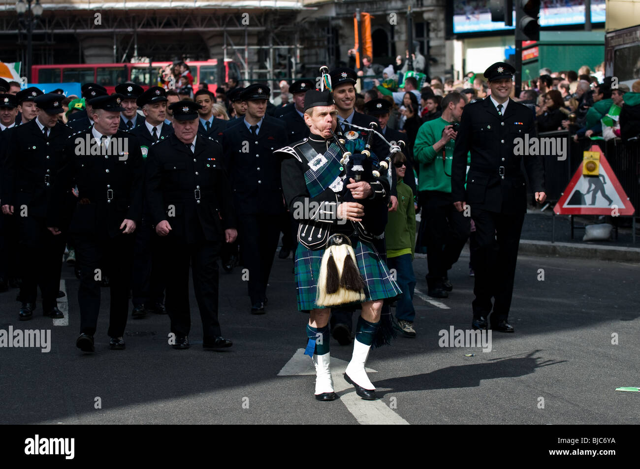 Ein Pfeifer führt eine Parade der Feuerwehr während der St. Patricks Day Parade in London. Stockfoto