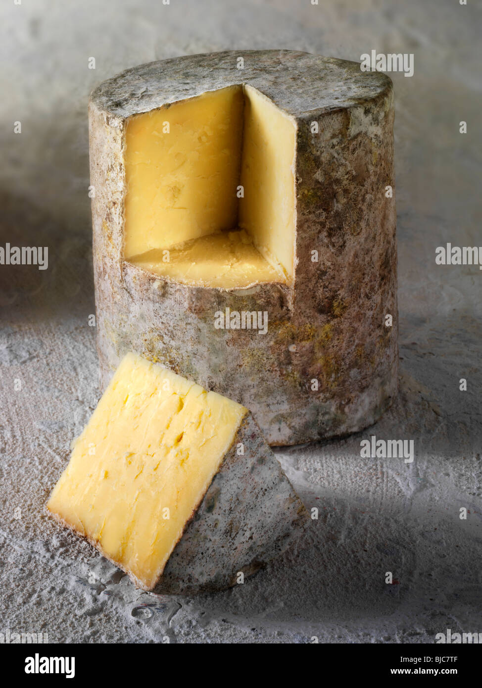 Traditionelle britische Bauernhaus Cheddar Käse Tuch gebunden truckle mit einem Keil ausgeschnitten Stockfoto