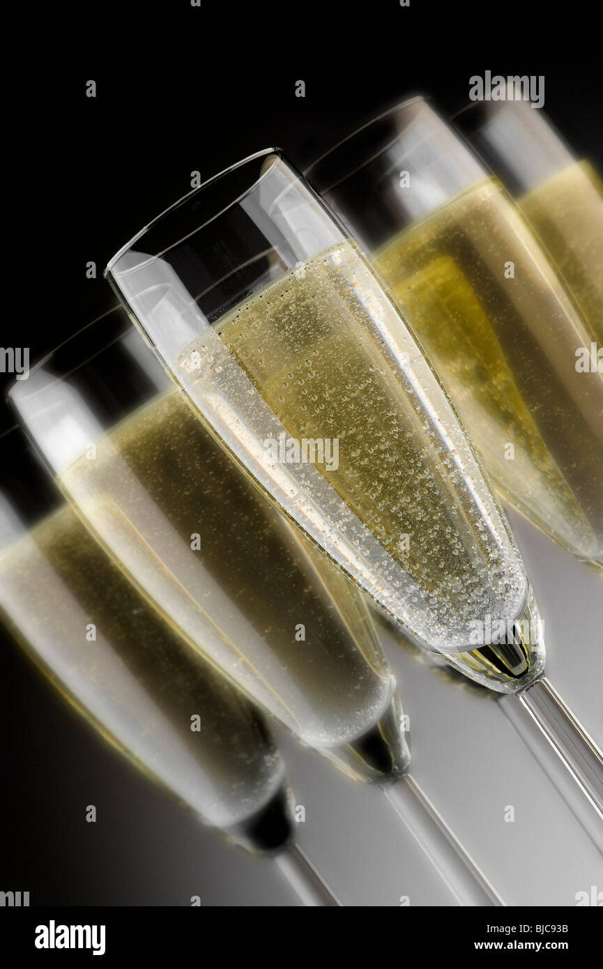 Studioaufnahme von Gläsern im Flötenstil, gefüllt mit Champagner auf dunklem, abgestuftem Hintergrund. Stockfoto