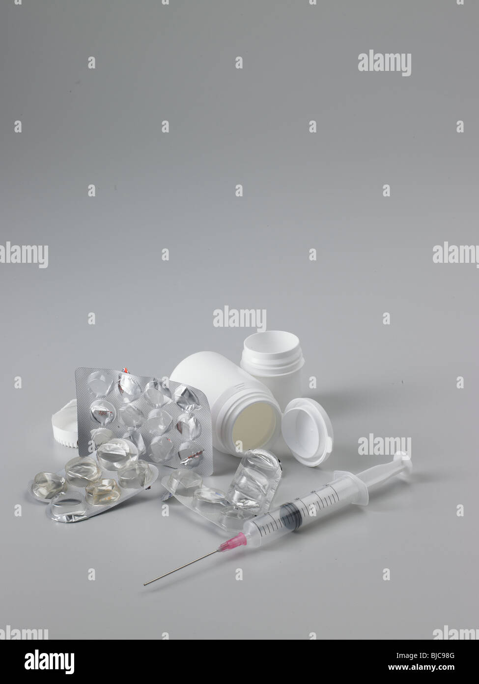 Pharmazeutische Verpackungen zu verschwenden und Spritze mit weißem Kunststoff Tablettenfläschchen in Hochformat und mittlere Ernte gedreht Stockfoto